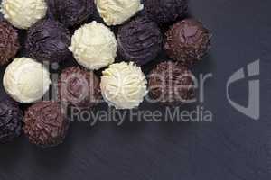 Truffles of fine chocolates on black stone background