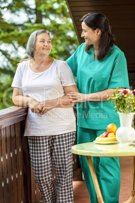 Female nurse consoling elderly woman at home
