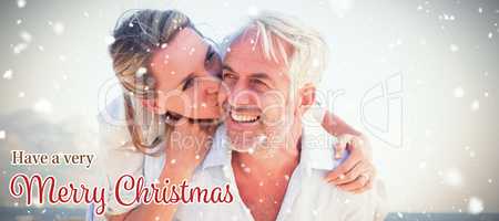 Composite image of man giving his smiling wife a piggy back at the beach