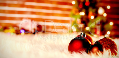 Composite image of red christmas balls on a white fur