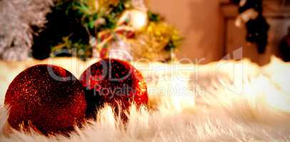 Composite image of two red christmas balls on a white fur