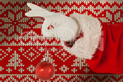 Composite image of santa claus holding christmas ornament