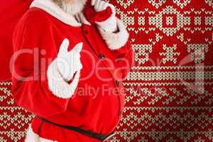Composite image of portrait of santa claus pointing while carrying christmas bag