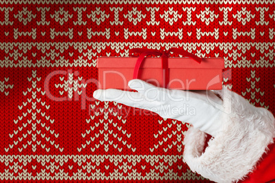 Composite image of santa claus holding gift box in hand