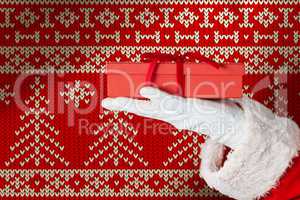 Composite image of santa claus holding gift box in hand