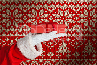 Composite image of santa claus holding a gift box in hand
