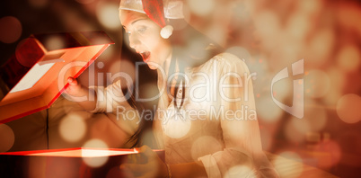 Composite image of festive brunette opening a glowing christmas gift