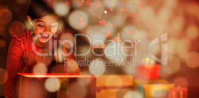 Composite image of little girl opening a glowing christmas gift