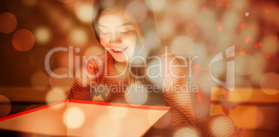 Composite image of little girl opening a glowing christmas gift