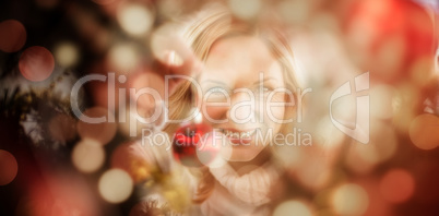 Composite image of festive blonde hanging bauble on christmas tree