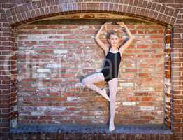 Cute Caucasian Ballerina Girl Posting Against A Brick Wall