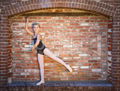 Cute Caucasian Ballerina Girl Posting Against A Brick Wall