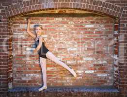 Cute Caucasian Ballerina Girl Posting Against A Brick Wall