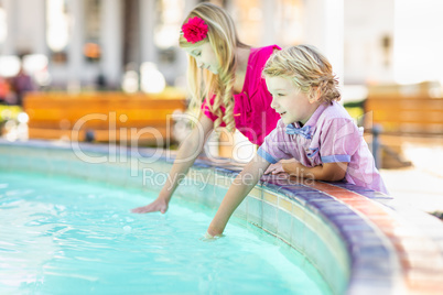 Cute Young Caucasian Brother and Sister Enjoying The Fountain At