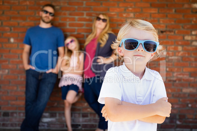 Cute Young Caucasian Boy Wearing Sunglasses with Family Behind