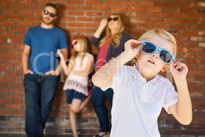 Cute Young Caucasian Boy Wearing Sunglasses with Family Behind