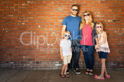 Young Caucasian Family Wearing Sunglasses Against Brick Wall