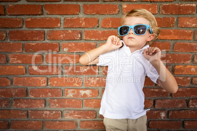 Cute Young Caucasian Boy Wearing Sunglasses Against Brick Wall