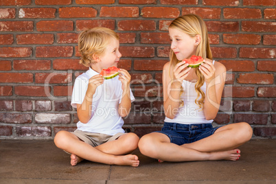 Cute Young Cuacasian Boy and Girl Eating Watermelon Against Bric