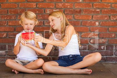 Cute Young Cuacasian Boy and Girl Eating Watermelon Against Bric