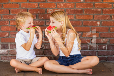 Cute Young Cuacasian Boy and Girl Eating Watermelon Against Bric