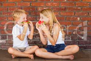 Cute Young Cuacasian Boy and Girl Eating Watermelon Against Bric