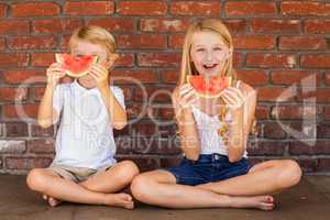 Cute Young Cuacasian Boy and Girl Eating Watermelon Against Bric