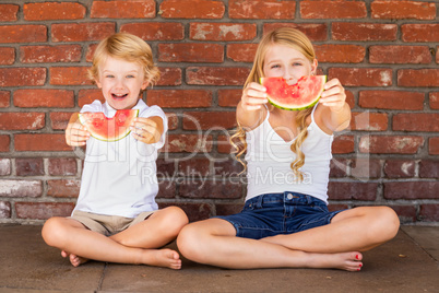 Cute Young Cuacasian Boy and Girl Eating Watermelon Against Bric