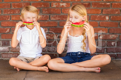 Cute Young Cuacasian Boy and Girl Eating Watermelon Against Bric