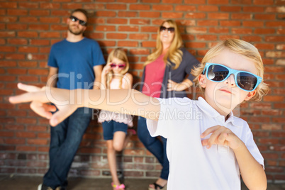 Cute Young Caucasian Boy Wearing Sunglasses with Family Behind