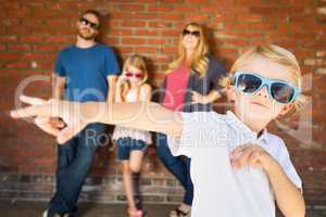 Cute Young Caucasian Boy Wearing Sunglasses with Family Behind
