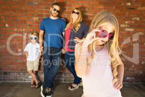 Cute Young Caucasian Girl Wearing Sunglasses with Family Behind
