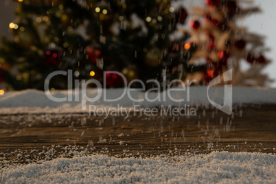 Wooden table with snow and unfocused Christmas tree