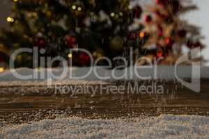 Wooden table with snow and unfocused Christmas tree