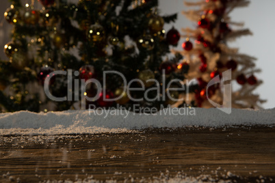 Wooden table with snow and unfocused Christmas tree