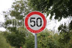 Round speed limit road sign on the road. 50 km per hour.