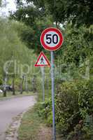 Round speed limit road sign on the road. 50 km per hour.