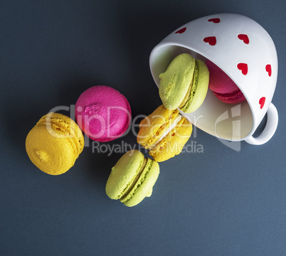 multicolored round cakes dropped out of a white ceramic cup