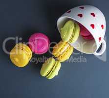 multicolored round cakes dropped out of a white ceramic cup