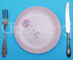 empty ceramic round pink plate and metal knife with fork