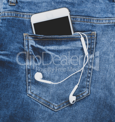 smartphone with headphones in the back pocket of blue jeans