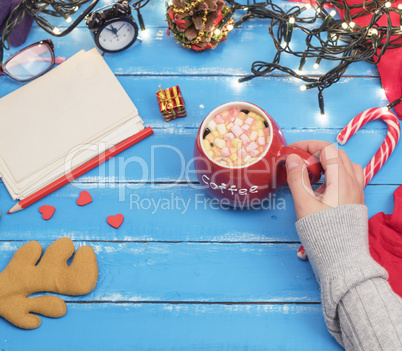 woman's hand holding a red ceramic mug with hot chocolate and ma