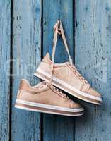 pair of beige fashionable female sports shoes hanging on a cord