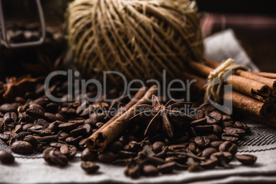 Coffee beans with autumn spices on the tablecloth.