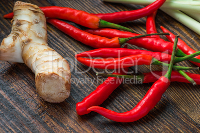 Galangal root, hot mini chili peppers with lemongrass on wooden table