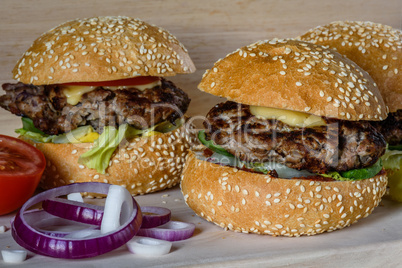 Three fresh burger lay on the board.