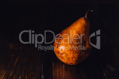 One Golden Pear on Wooden Background.