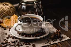 Cup of coffee with various spices, beans, leaves