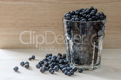 Blueberries in glass with scattered berries. Good addition for breakfast