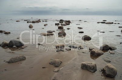 Sea waves splashing on the shore. Granite stones on a sandy beac
